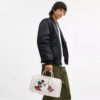 Geantă Disney X Coach Compass 35 cu Mickey Mouse